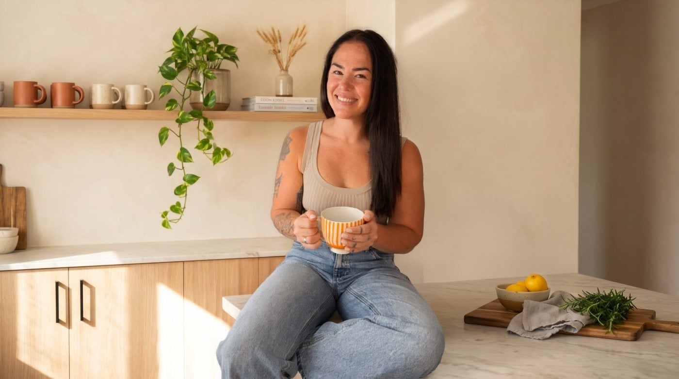 Teagan sitting on her kitchen bench holding a mug