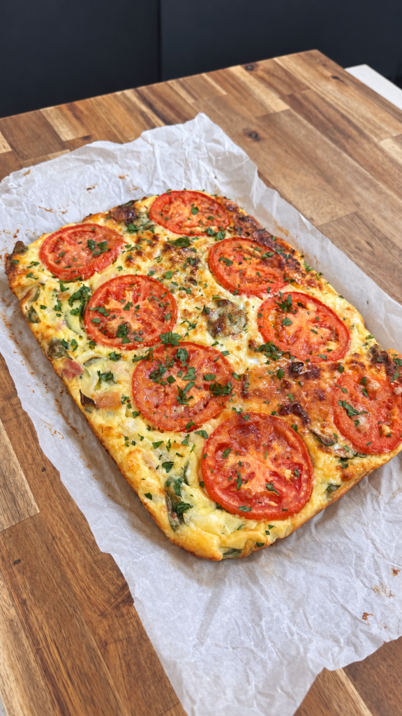 Easy high protein crustless quiche topped with sliced tomato and parsley